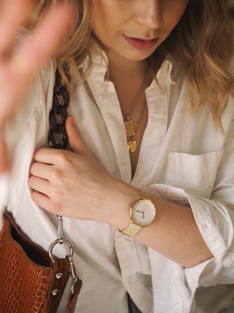 Close up of Nordgreen the Philosopher gold watch with white shirt and gold necklaces